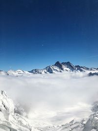 Scenic view of snowcapped mountains against blue sky