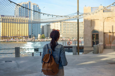 A young woman traveler walks enjoying the old narrow streets of dubai deira and creek. 