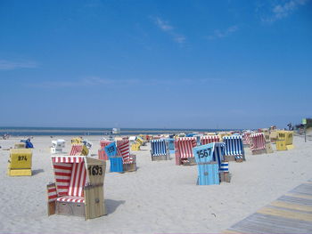 Hooded chairs at beach against sky