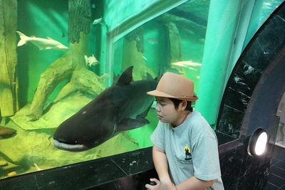 Young woman swimming in fish tank at aquarium