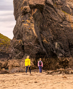 Rear view of two women walking on rock