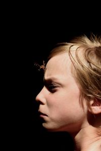 Close-up portrait of young woman against black background