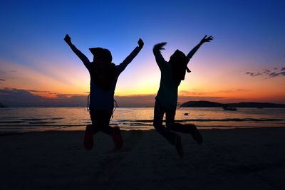 Silhouette people at beach against sky during sunset