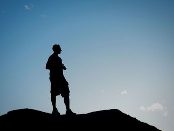 Silhouette man standing on rock against sky during sunset