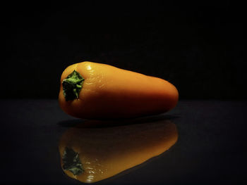 Close-up of orange slice on table against black background