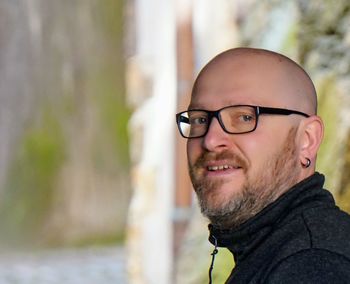 Side view portrait of smiling bald man wearing eyeglasses outdoors