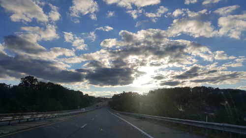 Empty country road against cloudy sky