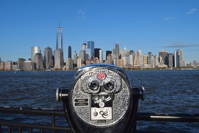 Coin-operated binocular against hudson river and one world trade center in city