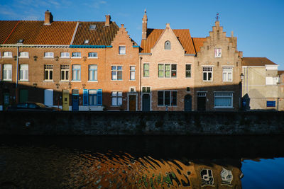 Buildings by canal against sky in city