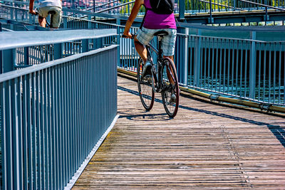 Low section of man riding bicycle on footbridge in city