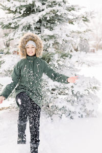 Portrait of smiling girl standing and playing with the snow