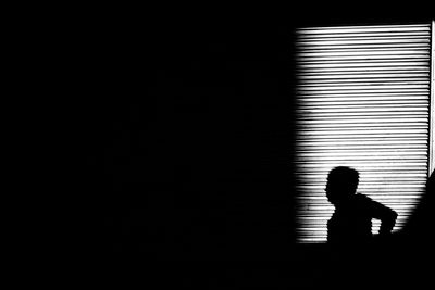 Silhouette boy against wall at night