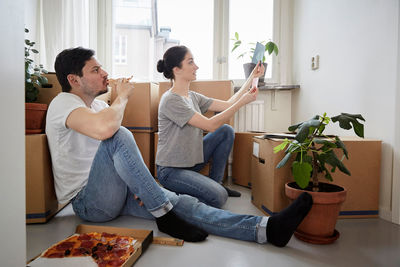 Man eating pizza while looking at woman choosing color swatches in new house