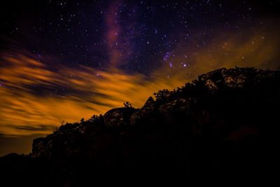 Low angle view of silhouette mountain against sky at night