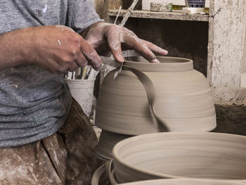 Midsection of man making pottery at workshop