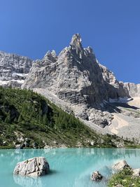 Scenic view of lake and mountains against clear blue sky