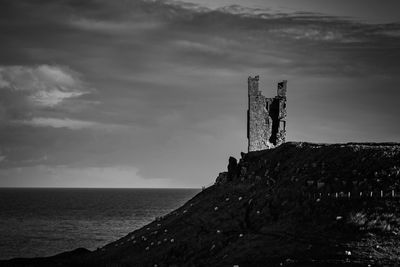 Traditional windmill on beach against sky