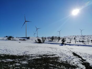 Windmills on field against clear sky during winter