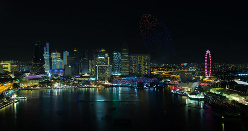 Illuminated modern buildings in city against sky at night