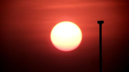 Close-up of illuminated lighting equipment against sky during sunset