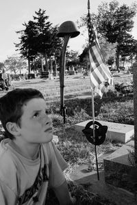 Portrait of boy holding umbrella against trees