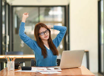 Portrait of young woman using mobile phone while sitting at office