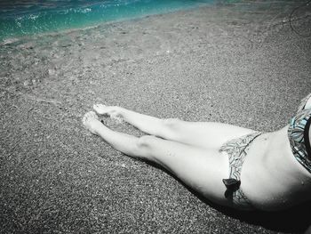 Low section of woman relaxing on beach