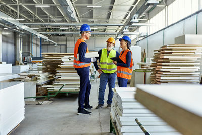 Colleagues in protective workwear talking in factory