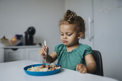 Girl sitting at table and eating meal