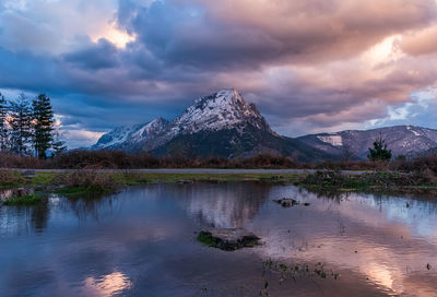 Scenic view of lake by mountains against sky during sunset