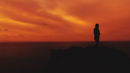 Silhouette man standing on beach against sky during sunset