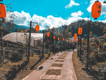 Road sign on footpath in city against sky