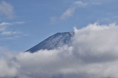 Low angle view of volcanic mountain against cloudy sky