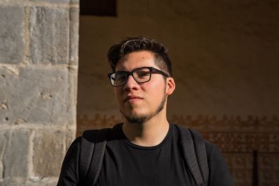 Portrait of young man standing against wall