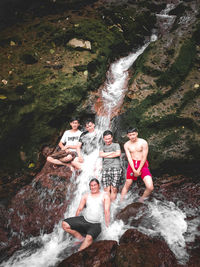 Full length of a young man with waterfall in water