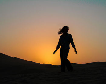 Silhouette woman standing against sky during sunset