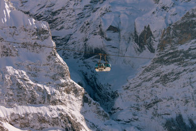 Overhead cable car hanging by snowcapped mountains