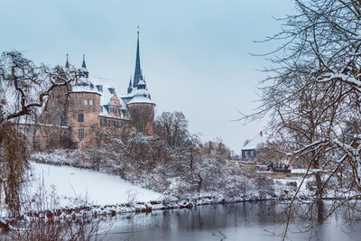 River amidst buildings against sky during winter