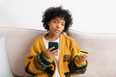 Portrait of young woman sitting on sofa at home