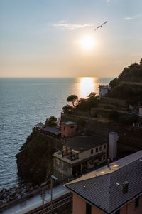 High angle view of buildings by sea against sky during sunset