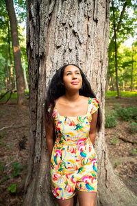 Full length of smiling woman standing on tree trunk