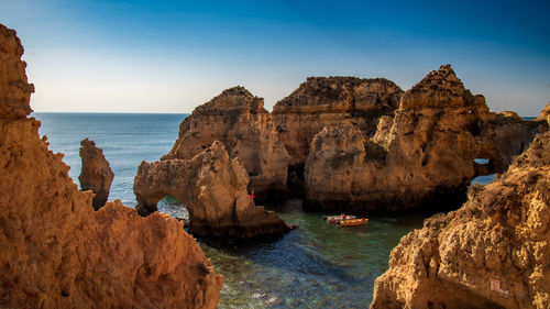 Rock formations by sea against sky