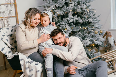 Happy friends sitting on christmas tree