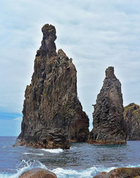 Rock formation on beach against sky