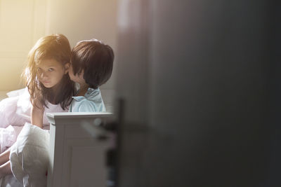 Girl and boy whispering at home