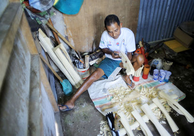 A craftsman finishes making a traditional salawaku shield weapon from cork wood in ternate city