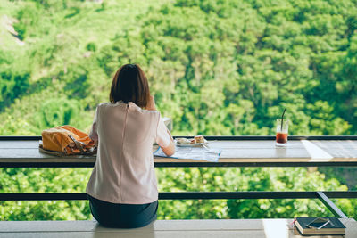 Rear view of woman sitting on table