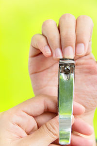 Close-up of person cutting fingernails over green background