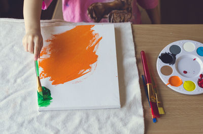 Midsection of girl painting on table