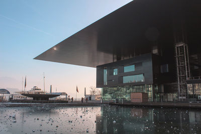 Buildings by river against sky in city